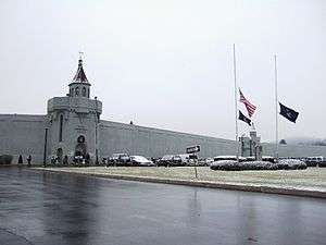 wall of building with text that says Attica Correctional Facility.  Flags are visible outside at half-staff.
