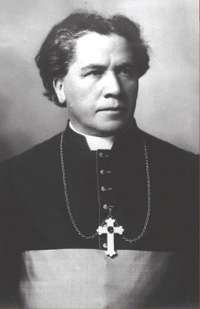 A man wearing a clerical collar and pectoral cross around his neck faces towards the right.