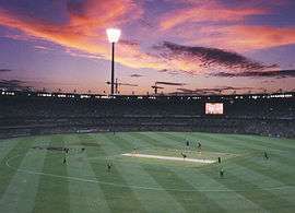 Brisbane Cricket Ground during an evening match, with the floodlights on.