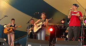 Photograph of Australian indie band FRUiT performing at Thundering Women music festival, 27 June 2004, Thunder Bay, Ontario, Canada with special guest Canadian singer/songwriter/guitar player Wendell Ferguson. FRUiT band members are (front row, left-to-right): Susie Keynes, Sam Lohs, Mel Watson.