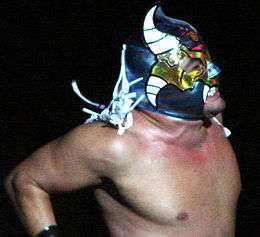 Closeup of a masked wrestler yelling; his mask has skull and horns markings on it
