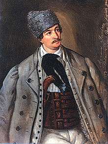 Mustachioed man in greatcoat and large hat