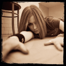 Avril Lavigne is shown lying on the ground and looking into the camera. There's no words in the pic.