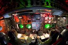 Lower deck of a B-52, with instruments and displays featuring dominantly on the aircraft's side wall. This station is manned by two crew members.