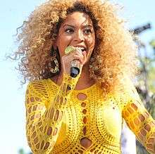 A profile picture of blonde woman wearing a yellow dress while performing