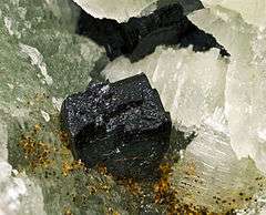 Shiny black crystals of babingtonite on whitish matrix.