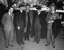 Five men in suits with hats and coats.