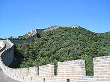 The Great Wall of China, surrounded by trees, against a blue sky