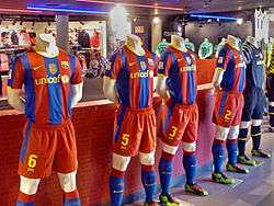 A number of jerseys, footballs and other association football equipment inside FC Barcelona's sports store.