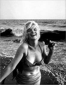 Monroe on a beach, wearing a bikini and laughing.