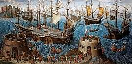 A small fleet of large, highly decorated carracks are riding on a wavy sea. In the foreground are two low, fortified towers bristling with cannons and armed soldiers and an armed retinue walking between them.