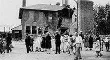 onlookers mill around, looking at the half-destroyed Bath School building
