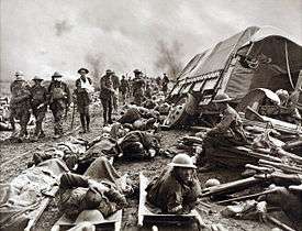 Injured soldiers lie amongst debris while others walk past nearby