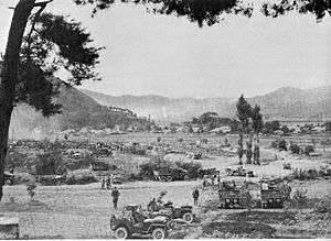 Trucks depart for a distant battlefield in the mountains where explosions can be seen