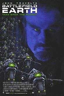 Movie poster which reads: John Travolta / Battlefield Earth / Take Back The Planet. A man's face with a goatee beard appears in the background, and alien spaceships in the foreground.