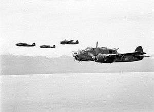 Four twin-engined military aircraft in low-level flight over the ocean