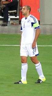 A photograph of a white man wearing association football attire while clapping his hands.