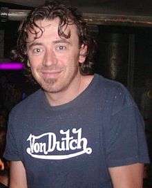 Benny Benassi smiling towards the camera. His curly hair falls on his face