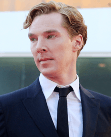 Benedict Cumberbatch facing left with blonde hair wearing a suit and tie