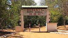 A dirt road runs under a decorated, arching sign demarcating the Berenty Private Reserve.