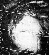 A satellite image of a hurricane. A small eye is visible. An overlay of the coordinate grid is also visible.