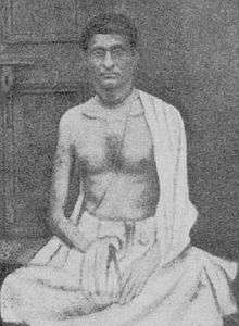 A young skinny Indian man sitting with chanting beads in hand