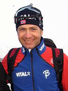 A man wearing a biathlete's racing gear, smiling into camera