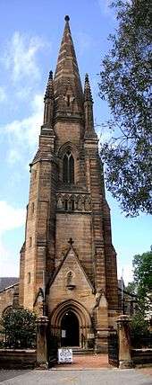 The spire of St John's, as described in the text. The main door, off the street, opens into the base of the tower. The door is open and there is a sign saying "Open church, all welcome to come in"