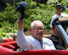 A man waving a cap in a car