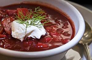A bowl of borscht garnished with dill and a dollop of smetana (sour cream)