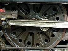An almost solid disc (not spoked) locomotive wheel with a series of cast-in radial indentations and prominent round holes intended to reduce its weight.