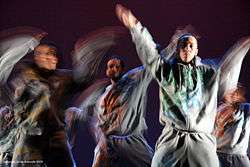 A close-up shot of a dance performance by five male hip-hop dancers in gray sweatsuits.