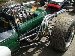Close-up of rear of a green racing car, showing the engine, exhausts, rear suspension and rear wheels