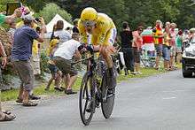 Bradley Wiggins riding a time trial bicycle wearing yellow cycling clothing.
