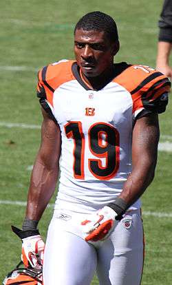An American football player walking on the field toward the camera. He is wearing a white jersey with the number 19 across the chest.