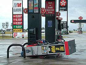 A gas pump laying on its side. The sign for the gas station is visible in the background.