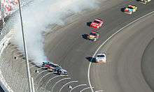 A car spinning sideways with white smoke coming from its rear-end