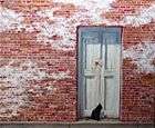 oil painting of worn, old, red-bricked building with spreading white mortar and white door, with jet black cat watching to right on the door threshold