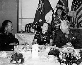 Two uniformed men talking to a woman at a dinner table