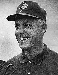 Candid black-and-white head-and-shoulders photograph of Grant smiling and wearing a Minnesota Vikings baseball cap