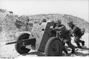 a black and white photograph of soldiers pushing a light artillery piece