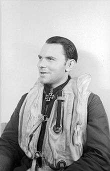 Smiling man wearing life jacket and a military decoration in shape of an Iron Cross at his neck.