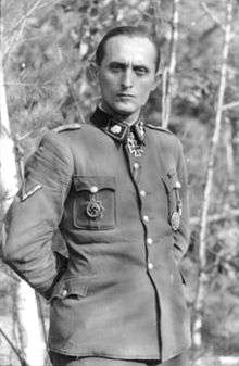 a man wearing a military uniform with various military decorations including an Iron Cross at his neck.