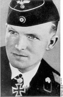 A black-and-white photograph of a man wearing a military uniform, side cap and a neck order in shape of an Iron Cross.