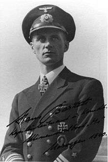 A man wearing a military uniform, peaked cap, and an Iron Cross displayed at the front of his uniform collar.