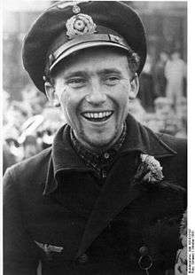 Black-and-white portrait of a smiling man with peaked cap.