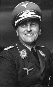 A smiling man wearing a military uniform and peaked cap.