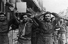 Soldiers surrendering some with their hands in the air other with them on their heads