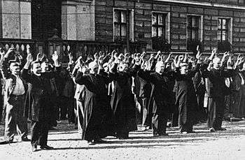 Prisoner priests and laypeople, with their hands up