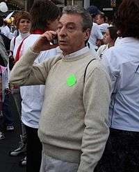 A man wearing a turtleneck shirt is holding a cellphone